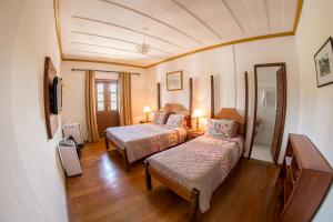 um quarto de hotel com duas camas e um espelho em Pouso Lar Doce Lar em Tiradentes