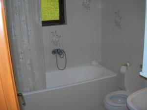 a white bathroom with a tub and a toilet at Emilios see view Apartment in Barbati