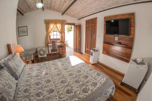 a bedroom with a bed and a flat screen tv at Pouso Lar Doce Lar in Tiradentes