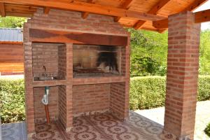 a brick fireplace in a patio with a wooden roof at Der Wald cabañas in Los Reartes