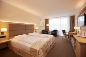 a hotel room with a large bed and a desk at Eibsee Hotel in Grainau +37 photos