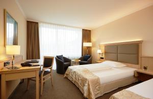 a hotel room with a bed and a desk at Eibsee Hotel in Grainau