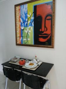 Shopping Motel Santa Maria do Pará في São Jorge: طاولة مع طبق من الطعام و لوحة على الحائط