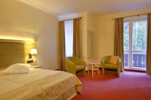 a hotel room with a bed and chairs and a window at Eibsee Hotel in Grainau