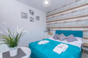 1 dormitorio con cama azul y pared de madera en Willa Riwiera, en Krynica Morska