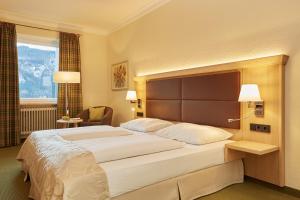 a large bed in a hotel room with two lamps at Eibsee Hotel in Grainau