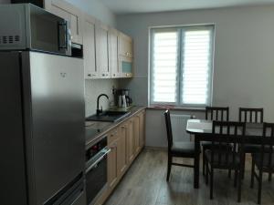 a kitchen with a stainless steel refrigerator and a table at Apartamenty Pisz in Pisz