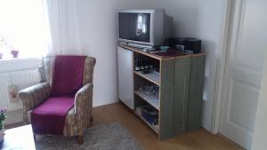 a living room with a tv and a chair at Bed en Broodje Bloem in Delft