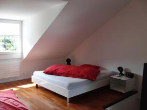 um quarto com uma cama branca e uma almofada vermelha em B&B Tomsi em Pratteln