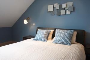 布永的住宿－La Petite Maison Maqua，一间卧室配有一张带蓝色墙壁和枕头的床