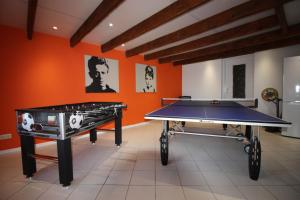 eine Tischtennisplatte in einem Zimmer mit orangefarbener Wand in der Unterkunft La Petite Maison Maqua in Bouillon