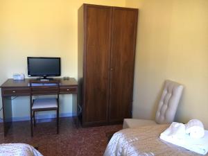 - une chambre avec un bureau, une télévision et une chaise dans l'établissement La Città degli Dei, à Agrigente