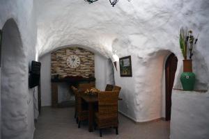 a dining room with a table and a clock on the wall at Casas Cueva con piscina y barbacoa in Fontanar