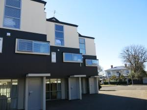 ein schwarzweißes Gebäude mit blauen Fenstern in der Unterkunft Merivale Apartments in Christchurch