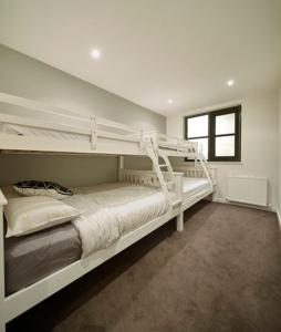 a white bedroom with two bunk beds in it at Alto Villa 304 in Mount Buller