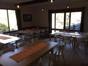 a dining room with tables and chairs and windows at Winterhaus Lodge Thredbo Village in Thredbo