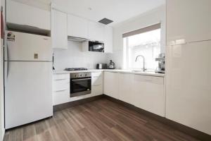 a white kitchen with white appliances and a wooden floor at Elkhorn 12 in Mount Buller