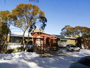 a house in the snow with a car parked in front at Elkhorn 7 in Mount Buller