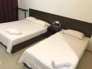 two beds in a hotel room with white sheets at Teluk Lipat Seaview Inn in Dungun