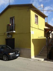 a black car parked in front of a yellow house at La Casetta Di Anna in Castel Lagopesole