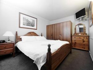 a bedroom with a bed and a dresser and a television at Twin Towers 502A in Mount Buller