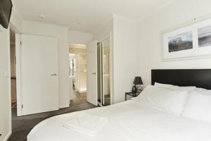 a bedroom with a large white bed and a mirror at Valley View 203 in Mount Buller