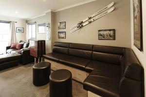 a living room with a large leather couch and stools at Valley View 203 in Mount Buller