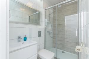 a white bathroom with a shower and a toilet at Willa Riwiera in Krynica Morska