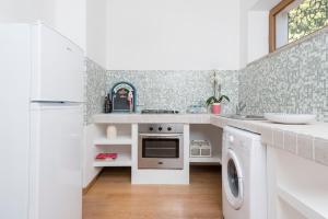una cucina bianca con lavatrice e asciugatrice di Villa con Terrazza Vista Mare a Castiglione della Pescaia