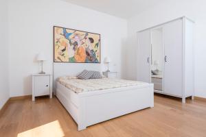 カスティリオーネ・デッラ・ペスカーイアにあるVilla con Terrazza Vista Mareの白いベッドルーム(ベッド1台付)が備わります。壁には絵画が飾られています。