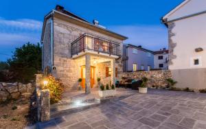 a stone house with a balcony and a patio at Holiday Home Eredità in Krk
