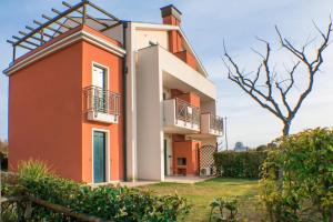 a red and white building with a tree at Residence Ca' D'Oro in Cavallino-Treporti