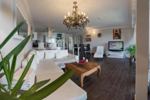 ein Wohnzimmer mit weißen Möbeln und einem Kronleuchter in der Unterkunft Residenz am Yachthafen in Cuxhaven