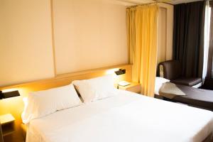 ein Schlafzimmer mit einem großen weißen Bett und einem Stuhl in der Unterkunft Hotel Les Jumeaux Courmayeur in Courmayeur