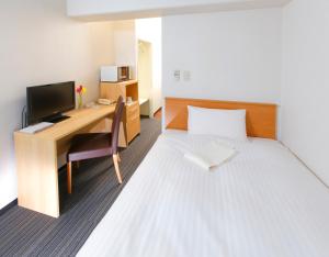 a room with a bed and a desk with a computer at FLEXSTAY INN Tokiwadai in Tokyo