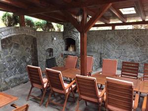 a wooden table and chairs on a patio with a stone fireplace at Pensiunea Görgő Panzió in Sfântu-Gheorghe