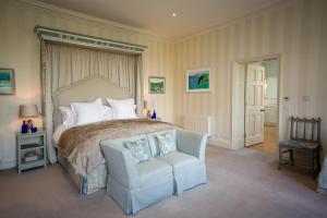 a bedroom with a large bed and a chair at The North Wing - Combermere Abbey in Whitchurch