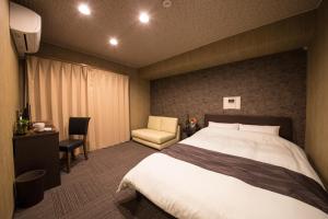a hotel room with a bed and a chair at Hotel CoCoDe Plus in Osaka