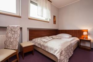 ein Schlafzimmer mit einem Bett, einem Stuhl und einem Fenster in der Unterkunft Hotel Barka in Kalwaria Zebrzydowska