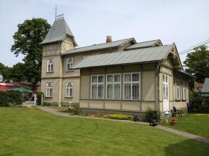 una casa grande con techo de gambrel y patio en Guesthouse Airava, en Jūrmala