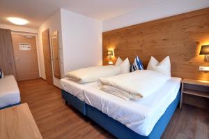ヴァルテンホーフェンにあるGästehaus zur Kroneの白いシーツと枕が備わるベッド1台が備わる客室です。
