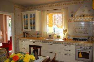 una cucina con armadi bianchi, lavandino e finestra di Villa Lucrezia a Reggello