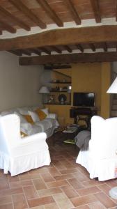 a living room with white chairs and a flat screen tv at Al Piccolo Ulivo, a casa di Mimo&Sè in Castiglione dʼOrcia