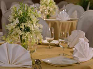a table with wine glasses and white flowers on it at Majestic Court Sarovar Portico in Navi Mumbai