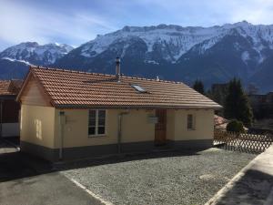 ein kleines gelbes Haus mit Bergen im Hintergrund in der Unterkunft Royal Swiss Apartments in Ringgenberg