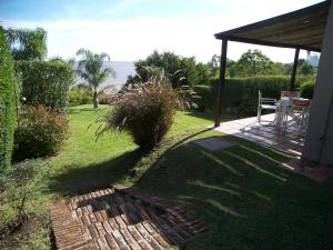 a patio with a table and a chair in a yard at Posada del Barranco Apart & Suites in Fray Bentos