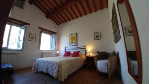 a bedroom with a bed with red pillows and a chair at Podere Sant'Angelo in Roccalbegna