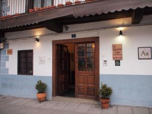 a building with a wooden door and two potted plants at Apartamentos La Iguana in Hervás