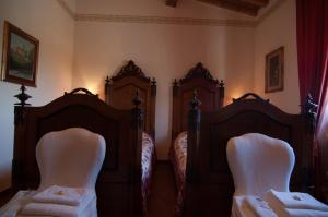 two twin beds in a bedroom with white chairs at Arpaderba B&B in Livorno