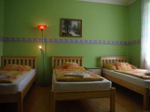 two beds in a room with green walls at Belvárosi Vendégház in Orosháza